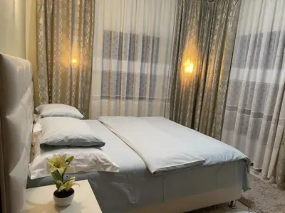 a small bedroom with a bed with white sheets and a table at Apartments Kalaja in Ulcinj