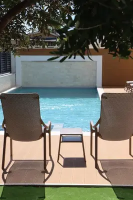 two chairs and a table next to a swimming pool at Apartmani Nilaj in Ulcinj
