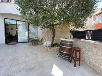 a patio with a barrel and a table and a tree at Apartmani Nilaj in Ulcinj