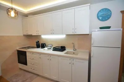 a kitchen with white cabinets and a white refrigerator at Apartments Olive in Kotor
