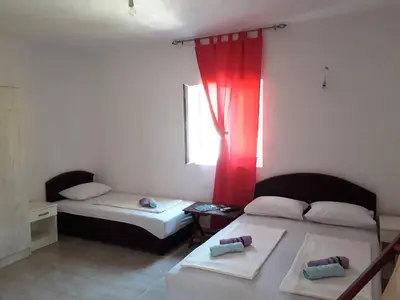 a bedroom with two beds and a window with red curtains at Apartmani Andrea-jaz in Budva