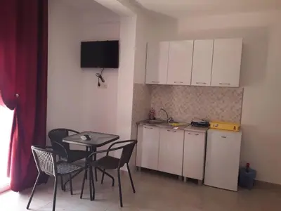 a kitchen with a table and chairs and a table and a kitchen with white cabinets at Apartmani Andrea-jaz in Budva