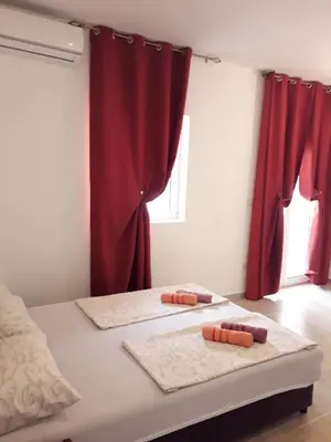 two mats on a bed in a room with red curtains at Apartmani Andrea-jaz in Budva