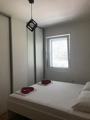 a bedroom with a bed with two red pillows on it at Apartman Tijana in Budva