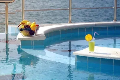 a bowl of fruit and a glass of juice in a swimming pool at Apartments Eneida in Ulcinj