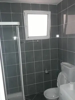 a bathroom with a shower and a toilet and a window at Flat Una in Budva