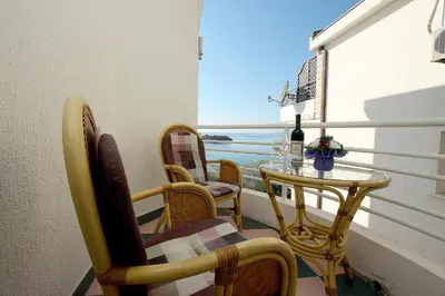 a balcony with chairs and a table and a window at Royal Holiday Apartments Sveti Stefan in Sveti Stefan