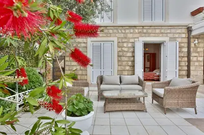 a patio with a couch and chairs and red flowers at Royal Holiday Apartments Sveti Stefan in Sveti Stefan