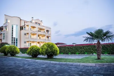 a building with a palm tree in front of it at Apart Hotel Llolla in Ulcinj