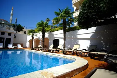 a swimming pool with lounge chairs next to a building at Hotel Kleopatra in Ulcinj