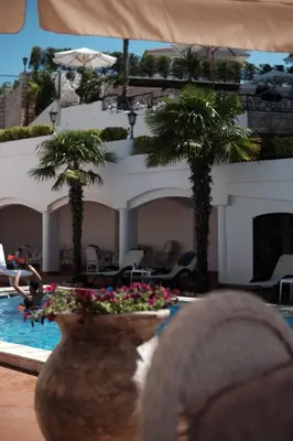 a hotel lobby with a pool and palm trees and a person at Hotel Kleopatra in Ulcinj