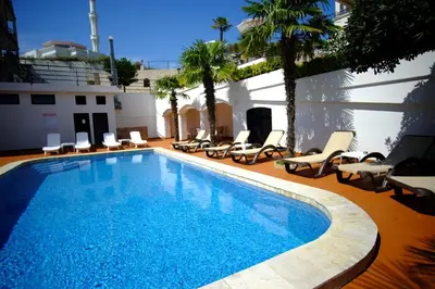 a large swimming pool with lounge chairs and a building at Hotel Kleopatra in Ulcinj