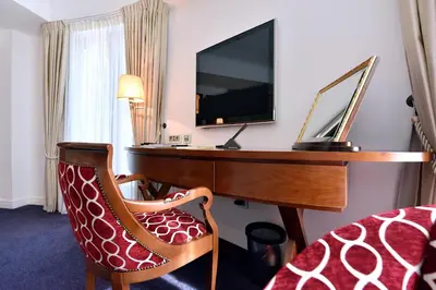 a hotel room with a desk and a chair and a television at Hotel Ziya in Podgorica