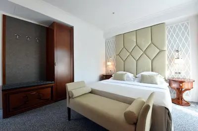 a bedroom with a large bed and a chair at Hotel Ziya in Podgorica