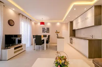 a kitchen and living room with a table and a television at Apartmani Matej in Kotor
