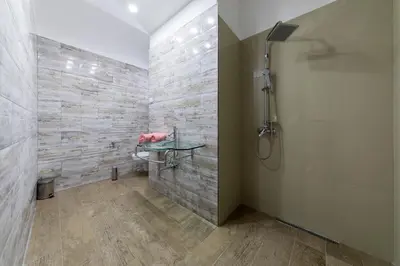 a bathroom with a shower and a stone wall at Villas Adriatic Horizonte in Budva