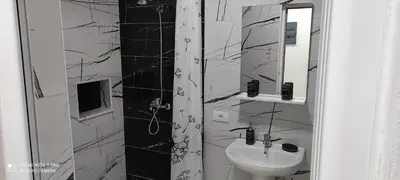 a black and white bathroom with a sink and a mirror at IdealHouse Apartments in Ulcinj