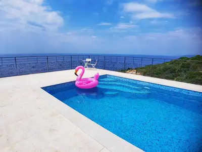 a pink swan in a swimming pool with the ocean in the background at Villa Nerin in Zagora
