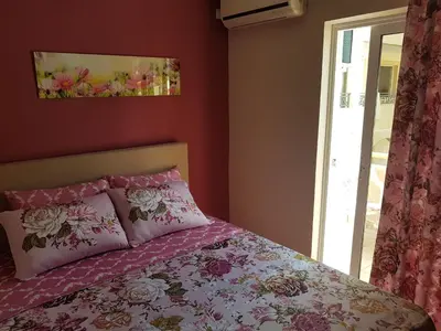 a bedroom with a bed with pink sheets and a window at Apartments Vila Galileo in Budva