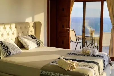 a bedroom with a bed and a balcony with a table at Villa Horus in Sveti Stefan