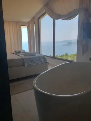 a bathroom with a tub and a bed and a large window at Villa Horus in Sveti Stefan