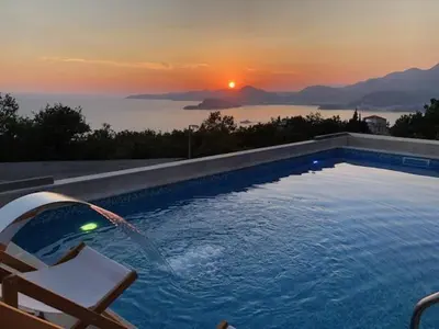 a swimming pool with a sunset in the background at Villa Horus in Sveti Stefan