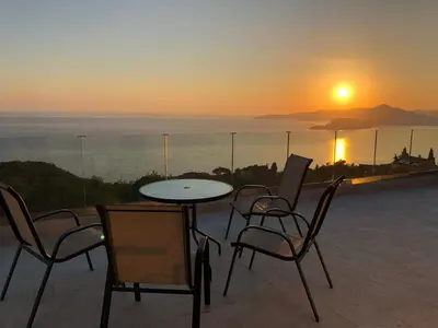 a table and chairs on a balcony with the sunset at Villa Horus in Sveti Stefan