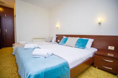 a bedroom with two beds with blue and white pillows at Hotel Odissey Jaz in Budva