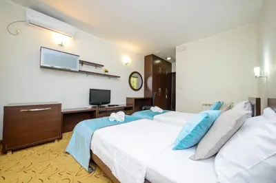 a bedroom with two beds and a desk and a television at Hotel Odissey Jaz in Budva