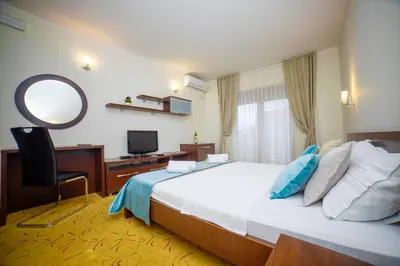 a bedroom with a bed and a desk and a mirror at Hotel Odissey Jaz in Budva