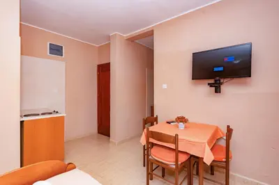 a dining room with a table and a tv on the wall at Villa Glavanovic in Bar