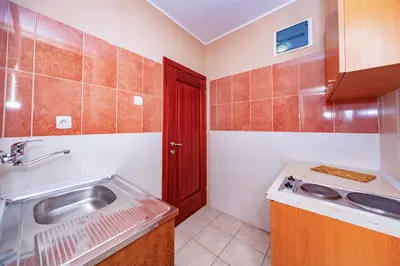 a small kitchen with a sink and a red door at Villa Glavanovic in Bar
