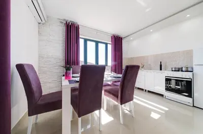 a dining room with a table and purple chairs at Alt Braic Villa in Budva