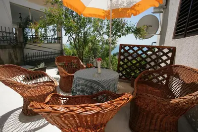 a table with wicker chairs and an umbrella on a patio at Apartments Cejovic in Ulcinj