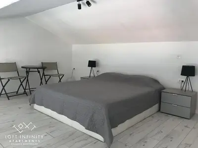 a bedroom with a bed and two tables and chairs at Loft Infinity in Petrovac na Moru