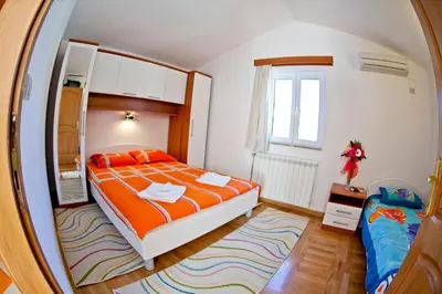 a bedroom with a bed with orange sheets and a mirror at Apartments Stefan in Becici