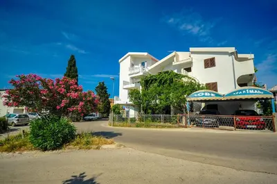 a white apartment building with pink flowers on a street at Apartmani Vitic in Bar