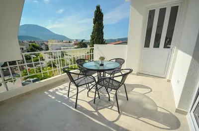 a patio with a table and chairs on a balcony at Apartmani Vitic in Bar