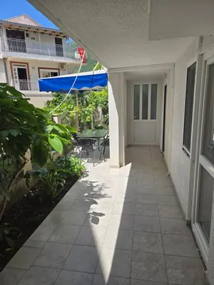 a patio with a table and a blue umbrella at Apartmani Vitic in Bar