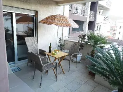 a patio with a table and chairs and an umbrella at Dvosoban stan, Babin Do, Budva sa garazom in Budva