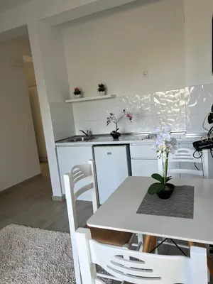 a white kitchen with a white table and chairs at Rasi Luxury Apartments in Ulcinj