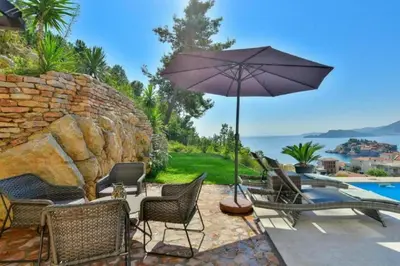 a patio with chairs and a table with an umbrella at Lux Apartment Luna in Sveti Stefan