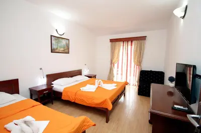 a hotel room with two beds and a flat screen tv at Apartmani More in Sveti Stefan
