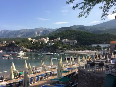 a beach with chairs and umbrellas and boats in the water at Harmony in Sveti Stefan