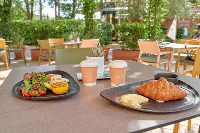 a table with two plates of food and cups of coffee at Hotel Harmonia by Dukley in Budva