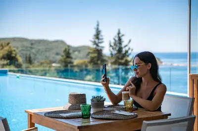 a woman sitting at a table taking a picture with her cell phone at Hotel Harmonia by Dukley in Budva