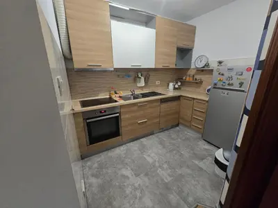 a kitchen with wooden cabinets and a stainless steel refrigerator at Recently renovated Delta Apartment in Podgorica