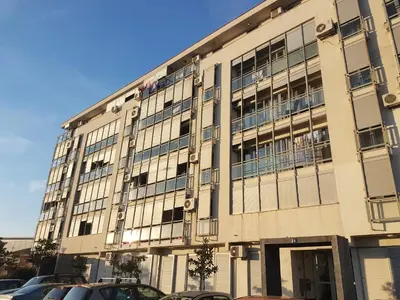 a large building with cars parked in front of it at Recently renovated Delta Apartment in Podgorica
