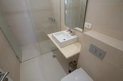 a white bathroom with a sink and a toilet at Villa Zen Port in Petrovac na Moru