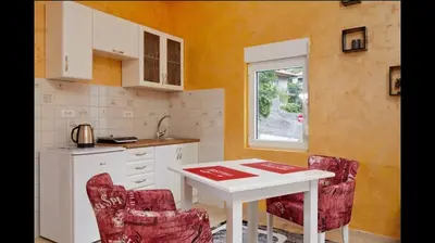a kitchen with a white table and two red chairs at Central Magik Apartments in Kotor